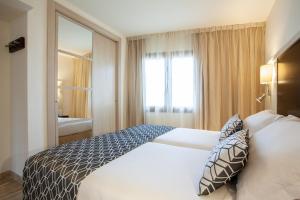 a bedroom with a white bed and a large window at Grupotel Los Príncipes & Spa in Playa de Muro