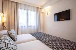 a hotel room with a bed and a flat screen tv at Grupotel Los Príncipes & Spa in Playa de Muro
