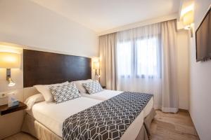 a hotel room with a large bed and a window at Grupotel Los Príncipes & Spa in Playa de Muro