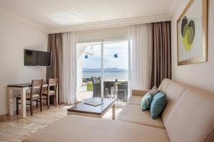 a living room with a couch and a view of the ocean at Grupotel Los Príncipes & Spa in Playa de Muro