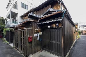 un edificio in legno con un cancello su una strada di Shiki Homes HARU a Kyoto