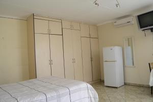 a kitchen with white cabinets and a white refrigerator at Sharon Rose Guesthouse in Windhoek