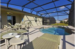 un patio con mesas y sillas y una piscina en Three-Bedroom Pool Home Kissimmee, en Orlando