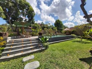 a garden with a bench and a swimming pool at Kirani Joglo Villa Bali by Mahaputra in Sukawati