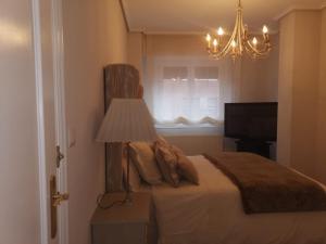 a bedroom with a bed with a lamp and a window at Habitación con baño privado en Bilbao in Bilbao