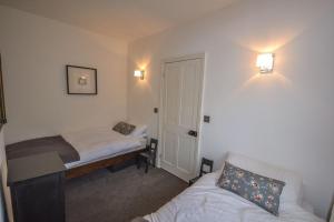 um pequeno quarto com 2 camas, uma mesa e um sofá em Guillemot em Beaumaris
