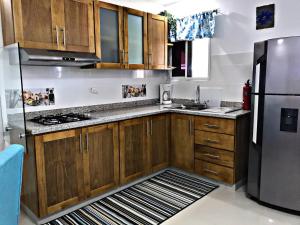 a kitchen with wooden cabinets and a stainless steel refrigerator at Charming 1b Apto Walk To The Beaches & Main Street in Sosúa