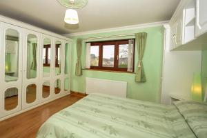 a green bedroom with a bed and a window at Simdde Wen in Beaumaris