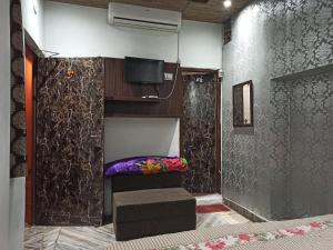 a room with a bed and a tv and a wall at Appna Ghar Hotel in Amritsar