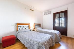 a bedroom with two beds and a red chair at Villa Mascota Rincón de la Victoria in Rincón de la Victoria +26 photos