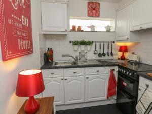 uma cozinha com armários brancos e um candeeiro vermelho em Little Willesleigh em Goodleigh