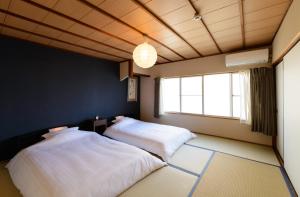2 camas en una habitación con ventana en Shiki Homes HIKARI en Kioto