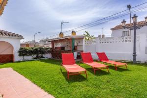 a group of red chairs sitting on the grass in a yard at Villa Mascota Rincón de la Victoria in Rincón de la Victoria