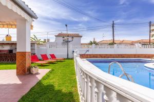 a pool with red chairs and a white fence at Villa Mascota Rincón de la Victoria in Rincón de la Victoria