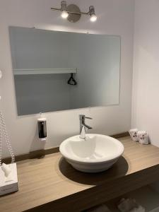 een badkamer met een witte wastafel en een spiegel bij Motel Le Rond Point in Metabetchouan