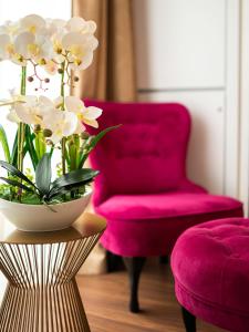 - un salon avec une chaise rose et une table fleurie dans l'établissement Luxury Studio Mamaia Nord, à Mamaia Nord – Năvodari