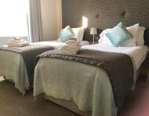 two beds in a hotel room with towels on them at Woodsome Hall Golf Club Dormy House in Fenay Bridge