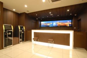 un bar con 2 taburetes y TV de pantalla plana en AB Hotel Iwata, en Iwata