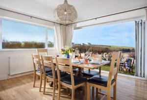 a dining room with a table and chairs and a large window at Trewalder in St Merryn