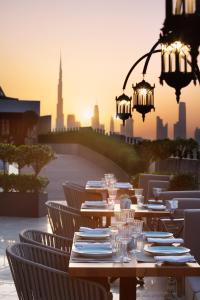 a table with plates and wine glasses in front of a city at Occidental Al Jaddaf, Dubai in Dubai