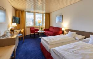 a hotel room with a bed and a red chair at Hotel Bayern Vital in Bad Reichenhall