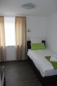 a bedroom with a bed with a green pillow at Hotel Tau-Lünne in Haselünne