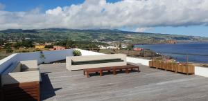 a wooden deck with a couch and a bench and the ocean at Sao Vicente Lodge - Atlantic Retreat in São Vicente Ferreira