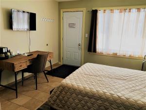 Little Current的住宿－山楂果汽車旅館，一间卧室配有一张桌子、一张床、一张桌子和一张书桌。