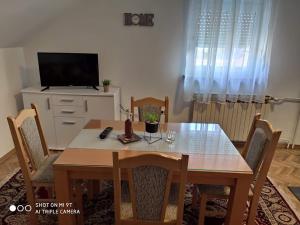 a dining room table with chairs and a television at Kaya 2 in Đakovo