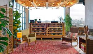 een bibliotheek met stoelen en een boekenplank met boeken bij Treehouse Hotel London in Londen