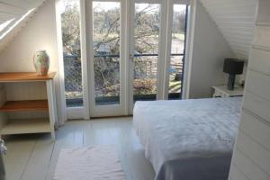 Schlafzimmer mit einem Bett und großen Fenstern in der Unterkunft Stråtækt idyl i skoven in Fredensborg