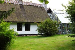 una vecchia casa con tetto di paglia e cortile di Stråtækt idyl i skoven a Fredensborg