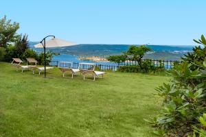 a group of chairs and an umbrella on a grass field at Villa Regina Bella by Casa da Suite in Nebbiuno
