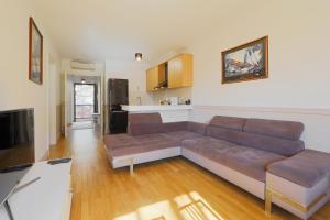 a living room with a brown couch and a kitchen at The Bluedeck Wellness Apartment in Balatonfüred