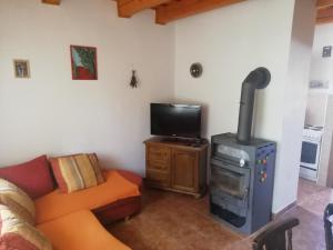 a living room with a stove and a couch and a tv at Chata Hájik Podhajska in Podhájska