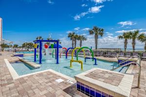 a beach with a pool, chairs, tables and umbrellas at Dunes Village in Myrtle Beach