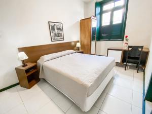 a bedroom with a bed and a desk and a window at Pousada Colonial Chile in Salvador