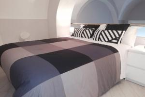 una camera con letto bianco e nero con cuscini di Palazzo D'Arrigo White Loft a Catania