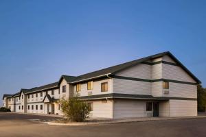 a large white building with a black roof at Travelodge by Wyndham Pecos in Pecos