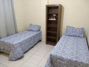 a bedroom with two beds and a book shelf at SENA'S APART in Muriaé