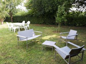 grupa krzeseł i stołów w trawie w obiekcie Large holiday home with garden in Brittany w mieście Hénansal