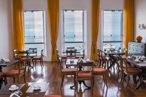 a dining room with tables and chairs and windows at Pousada Colonial Chile in Salvador