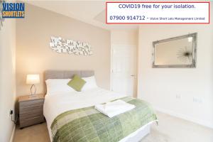 um quarto com uma cama com um cobertor verde e branco em Station Suites em Watford