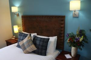 a bedroom with a bed with pillows and a blue wall at Craiglynne Hotel in Grantown on Spey