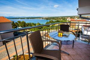 a balcony with a table and chairs and a view of the water at Apartments Mare & Mons Deluxe in Malinska