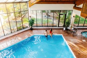 two people in an indoor swimming pool with windows at Chateau Jasper in Jasper