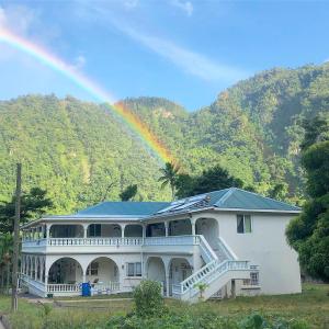 a rainbow over a large white house with at Soufriere Guesthouse in Soufrière