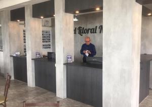 a man standing at a reception desk in a building at Hotel Litoral Norte in Caraguatatuba