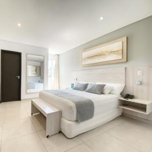 a white bedroom with a large bed and a mirror at Danieri Asunción Hotel in Asuncion