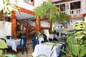 a restaurant with white tables and blue chairs and plants at Hotel Colonial - Honda - in Honda